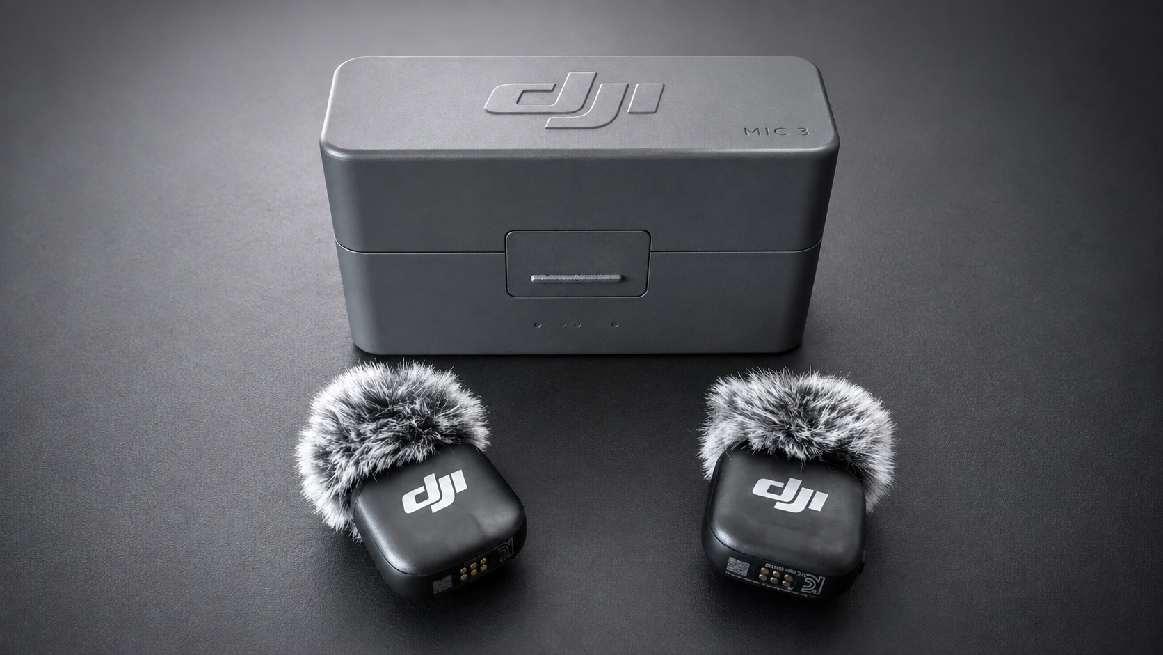 Zwei DJI Mic 3 Sender mit Windschutz vor dem geschlossenen Ladecase